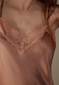 Camisón de satén rosa con un delicado escote de encaje, tirantes ajustables y una textura suave y lisa.