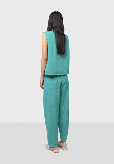 Turquoise ribbed two-piece outfit featuring a sleeveless top and loose-fitting pants with a back pocket, highlighting a textured fabric.