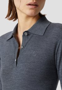 Polo grigio antracite realizzato in tessuto testurizzato. Caratterizzato da un collo a polo, una chiusura con tre bottoni e un piccolo dettaglio logo ricamato.