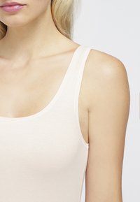 Helles pinkes Tanktop aus dehnbarem Material, mit breiten Trägern und einem runden Halsausschnitt, entworfen für eine enge Passform auf der Haut.