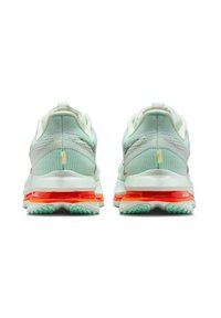 Light green running shoes with a textured upper, visible air cushioning in the heel, and bright orange accents on the sole.