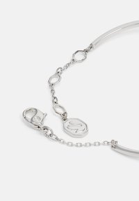 Bracciale in argento con una barra di metallo curva e liscia, sezioni di catena ottagonali collegate e un clasp a gabbiano con un charm esagonale texturizzato.