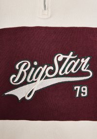 Kremas ir bordeaux spalvų ketvirčio užtrauktuko megztinis, su balta siuvinėta "Big Star" užrašu žaliu kontūru ir numeriu "79".