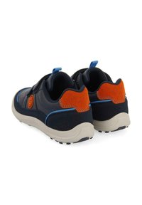 Baskets navy avec des accents en daim orange, des coutures bleues et une semelle texturée. Comprend une sangle à crochets et boucles pour un maintien sécurisé.