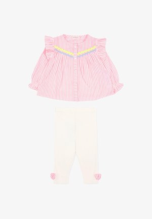 Blouse à manches longues rayée rose et blanche avec volants et bordure jaune-bleu, associée à des leggings blancs ornés de nœuds rayés roses au niveau des chevilles.