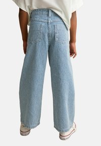 Vidbyxor i randig denim med hög midja, två bakfickor och en lös passform, kombinerat med vita sneakers.