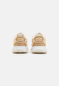Sneakers con una base bianca e pannelli in rete color pesca e beige, colli imbottiti e dettagli testurizzati, progettati per comfort e supporto.