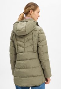 Oliwkowa, ocieplana kurtka z kapturem, o pikowanej konstrukcji i bocznych kieszeniach, prezentująca teksturowany, miękki materiał.