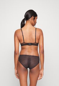 Svart blonde BH med justerbare stropper og lukking bak med krok, kombinert med matchende høyt liv-bunn med et teksturert mønster.