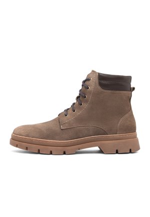 Brauner Wildleder-Knöchelstiefel mit dunkelbraun gepolstertem Kragen, schwarzen Schnürsenkeln und dicker Gummisohle mit tiefem Profil, im Profil nach links gezeigt.