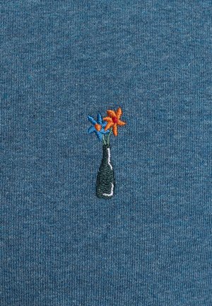 Embroidered design on a blue textured fabric features a black bottle with orange and blue flowers, showcasing distinct color contrast and detail.