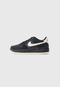 Jūras zilas zamšādas tenisa apavi ar melniem akcentiem un baltu Nike diognālu. Iezīmējas ar gumijas zoli un perforētu purngali, kas nodrošina elpojamību.