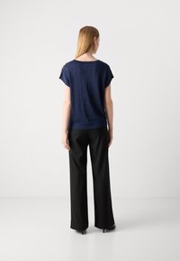 Navyblaues Strickoberteil mit kurzen Ärmeln und lockerer Passform, mit strukturiertem Finish und geripptem Saum, kombiniert mit schwarzen weiten Hosen.