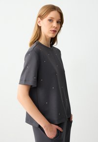 Grijze sweatshirt met korte mouwen versierd met kleine zilverkleurige accenten, met een ronde halslijn en een losse pasvorm voor comfort.