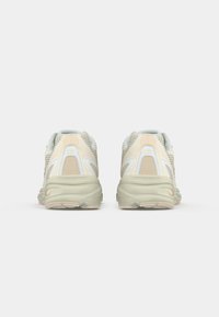 Scarpe da corsa in crema chiaro e verde menta, con una tomaia in rete, suola imbottita e un design unico del tallone con accenti sottili.