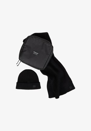 Zwarte geribbelde gebreide sjaal, bijpassende muts en een zwarte pouch met rits en Strellson-logo op een witte achtergrond.