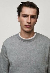 Hanorac gri cu guler clasic, fabricat din material de bumbac moale. Are un finisaj texturat și un design minimalist fără modele.