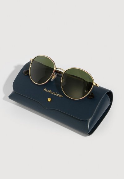 Runde solbriller med rammer i gult metall og mørke linser som hviler på et marineblått Polo Ralph Lauren-etui med gullklips.