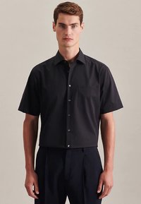 Camicia nera a maniche corte realizzata in tessuto liscio, con colletto, chiusura con bottoni e taschino sul petto. Vestibilità sartoriale con design pulito.