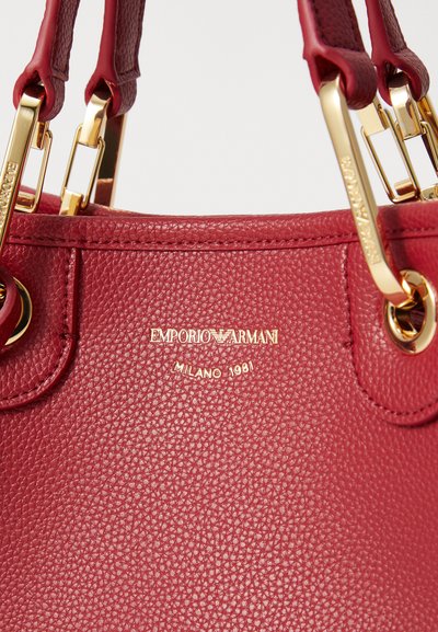 Geantă din piele texturată roșie cu detalii aurii. Prezintă logo-ul embosat "Emporio Armani Milano 1981" pe față. Design cu două mânere.