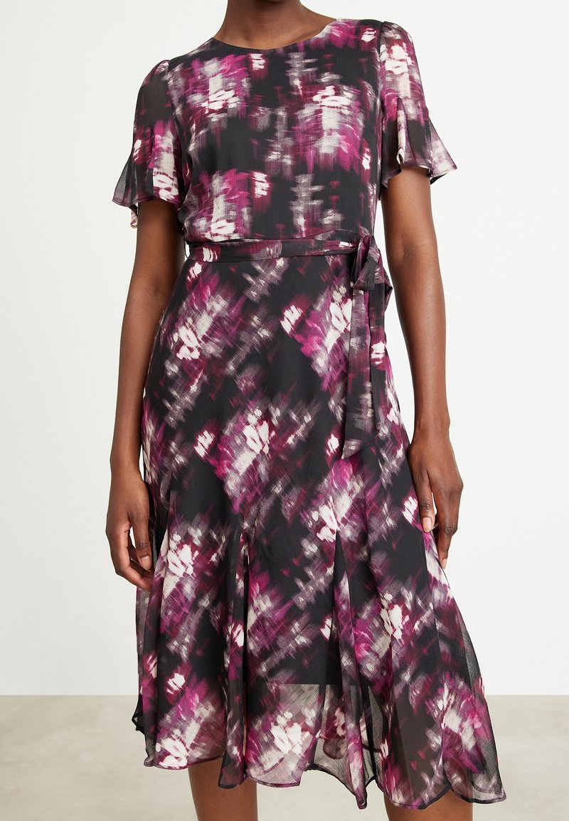 Svart klänning med ett flerfärgat abstrakt mönster i nyanser av rosa och vitt. Har korta volangärmar och en knytskärp i midjan.
