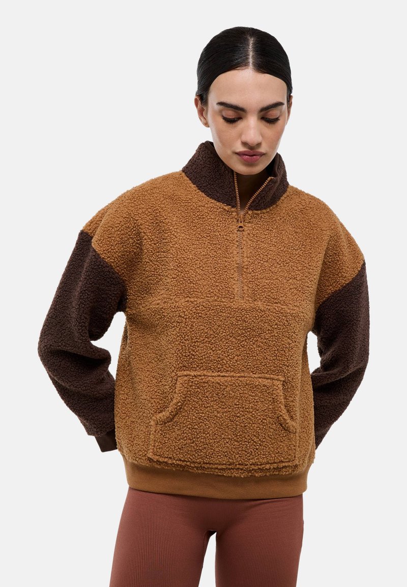 Pull en polaire marron avec un col à demi-fermeture éclair, des manches foncées contrastées, une poche avant et une surface texturée.
