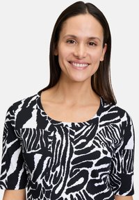 Top a righe bianco e nero con design a stampa zebra, maniche corte e scollo rotondo, con un aspetto di tessuto testurizzato.
