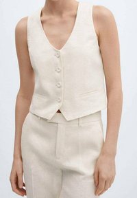 Lniowana kamizelka w jasno beżowym kolorze z dekoltem w serek, z pięcioma guzikami i dwiema przednimi kieszeniami; krótki fason o gładkiej fakturze.