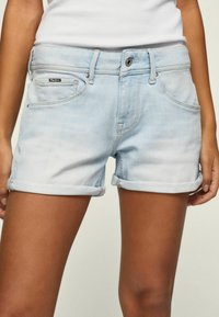Szorty dżinsowe, jasnoniebieskie, z podwiniętymi nogawkami, prosty krój, z dwoma przednimi kieszeniami. Posiadają metkę marki w pobliżu pasa.