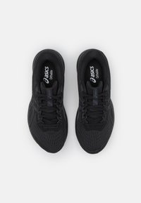 Chaussures de sport noires avec une tige en mesh et une finition texturée, dotées de lacets, de semelles rembourrées et du logo imprimé sur les semelles intérieures.