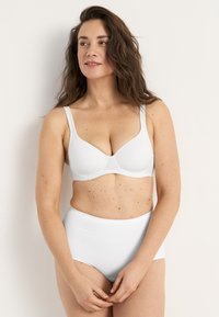 Weißer modellierter BH mit breiten Trägern und glatter Oberfläche, kombiniert mit hochgeschnittenen weißen Slips. Beide Teile haben ein nahtloses Design.