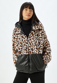 Leopardmønstret fleecejakke med en nederste sektion i sort nylon. Den har en lynlåslukning foran, hætte og dropped skuldre for en afslappet pasform.