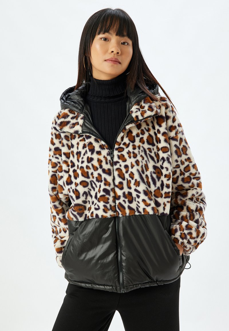 Leopardmønstret fleecejakke med en nederste sektion i sort nylon. Den har en lynlåslukning foran, hætte og dropped skuldre for en afslappet pasform.