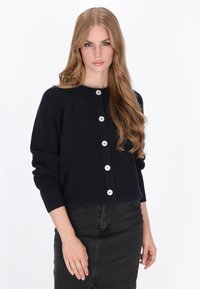 Cardigan a coste blu navy con scollatura rotonda, chiusura a bottoni e maniche lunghe. Caratterizzato da grandi bottoni bianchi e design corto.