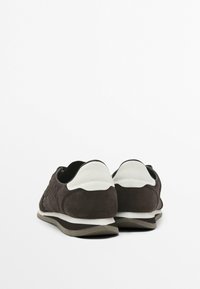 Sneakers in suede marrone con un accento in pelle bianca sul tallone, caratterizzati da un design testurizzato e una suola in gomma.
