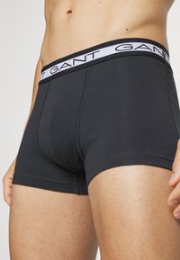 Black cotton boxer briefs with a white GANT logo waistband, featuring a snug fit and smooth texture, highlighting stitching details.