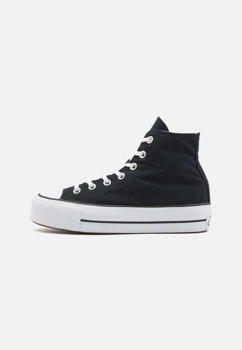 High-top canvas sneakers in black with white rubber toe cap, white laces, and a textured black upper. Black and white striped midsole.