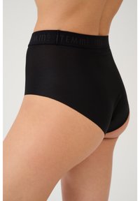 Mutande nere a vita alta con una texture liscia, dotate di una cintura tonale con il nome del marchio ITEM m6 delicatamente impresso.