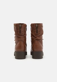 Botas de cuero marrón hasta el tobillo con un diseño arrugado, que cuentan con dos cremalleras en la parte trasera y un tacón cuadrado resistente. Detalle de superficie texturizada.