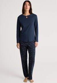 Navy long-sleeve top with a keyhole neckline paired with star-patterned pajama pants. Soft fabric and relaxed fit for comfort.
