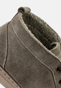 Botine gri din suede, cu căptușeală interioară texturată, detalii de cusături și un bucată de tragere în spate pentru o încălțare ușoară.