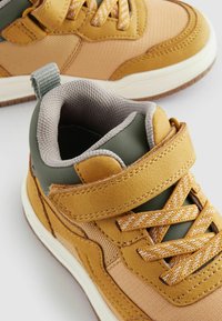 Hoge sneakers met een mix van mosterdgeel en olijfgroen materiaal, gestructureerde stof, een gewatteerde kraag en een klittenbandsluiting.