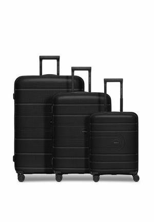 Trois valises rigides noires de tailles variées, présentant une surface texturée, des poignées télescopiques et des roues roulantes fluides.