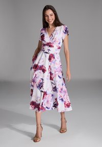 Bloemige midi-jurk met een aansluitende lijfje, V-halslijn, korte mouwen en zakken. Heeft paarse en rozen bloemen op een witte achtergrond.