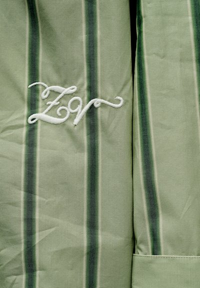 Πράσινο ύφασμα με κάθετες σκούρες και ανοιχτές πράσινες ρίγες, με λευκά κεντημένα γράμματα με καλλιγραφικό χαρακτήρα "Z9".