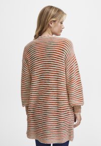 Stickad kofta med lös passform, med horisontella ränder i orange, beige och brunt. Långa ärmar och rundad nederkant.