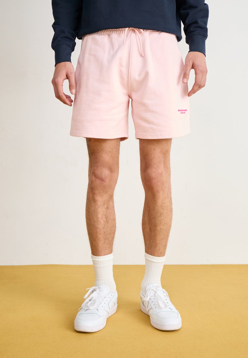 Lys pink bomulds-shorts med elastisk talje og snor, med et lille kontrastlogo ved kanten. Glat tekstur.