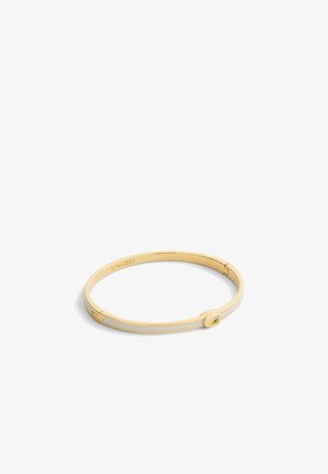 Guldtonet bangle armbånd med en glat overflade, cirkulært lås og minimalistisk design med indgraverede detaljer.
