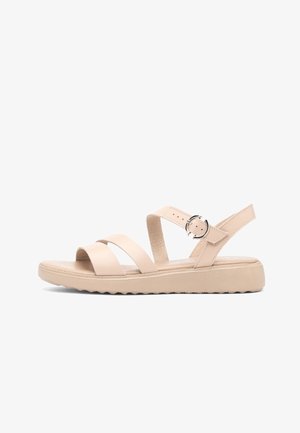 Beżowa płaska sandałka z dwoma paskami z przodu, paskiem na kostkę z okrągłą srebrną klamrą oraz miękką podeszwą z teksturowanym spodem dla lepszej przyczepności.