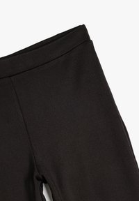 Leggings en tissu extensible noir avec une texture lisse et une large ceinture, présentant un design élégant et sans coutures visibles.